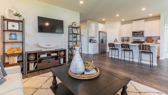 living room with recessed lighting, dark wood-type flooring, and baseboards