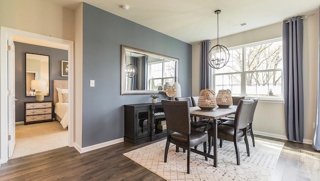 dining space featuring visible vents, wood finished floors, baseboards, and a chandelier