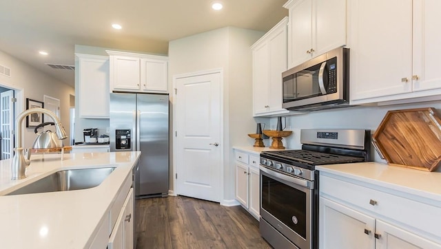 kitchen featuring appliances with stainless steel finishes, white cabinetry, light countertops, and a sink