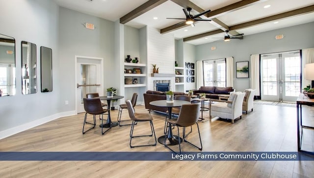 dining space with french doors, beamed ceiling, a stone fireplace, and wood finished floors