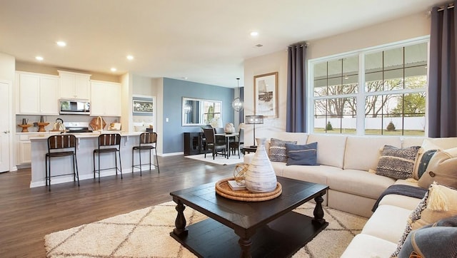 living area with recessed lighting, dark wood-type flooring, and baseboards