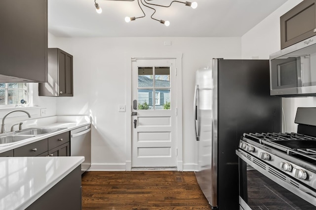 kitchen with dark wood-type flooring, baseboards, light countertops, stainless steel appliances, and a sink