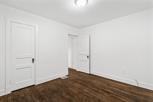 empty room with visible vents, baseboards, and dark wood-style flooring