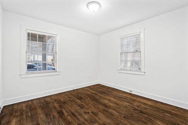 empty room featuring baseboards and dark wood-type flooring