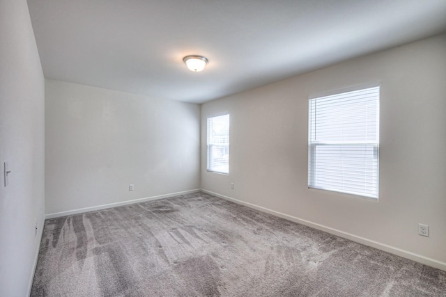 empty room featuring baseboards and carpet