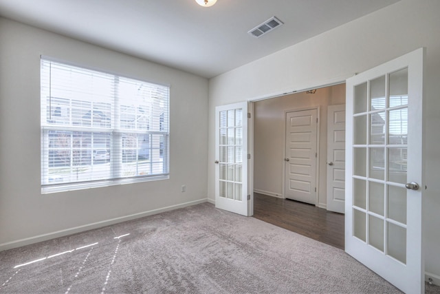 carpeted spare room with french doors, visible vents, and baseboards