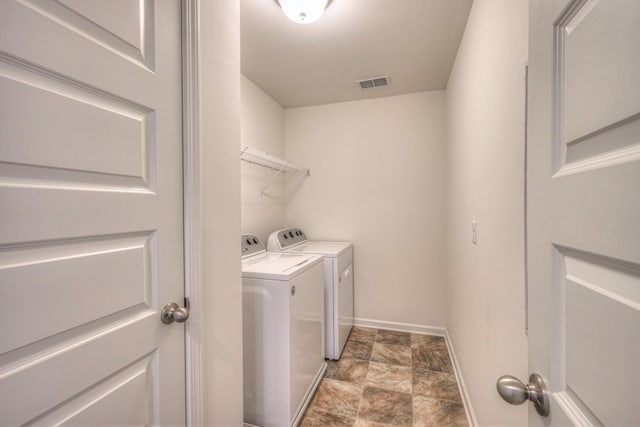 washroom with visible vents, washer and dryer, stone finish flooring, baseboards, and laundry area