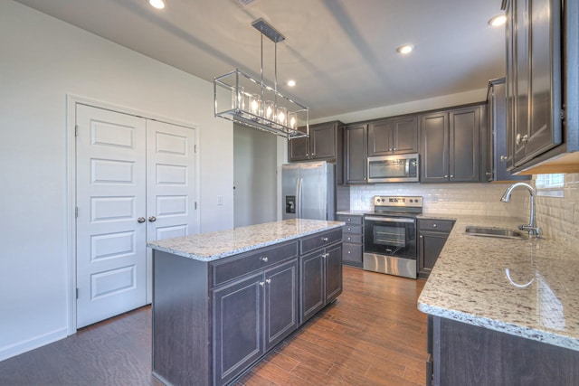 kitchen featuring dark wood-style flooring, backsplash, appliances with stainless steel finishes, and a sink