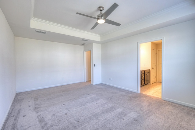 unfurnished bedroom featuring light colored carpet, crown molding, a raised ceiling, and baseboards