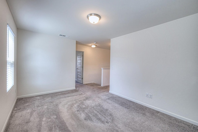 carpeted spare room featuring visible vents and baseboards