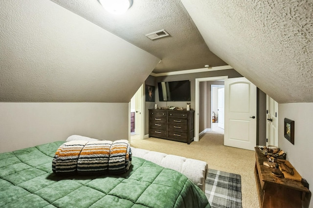 bedroom featuring visible vents, light colored carpet, a textured ceiling, and vaulted ceiling