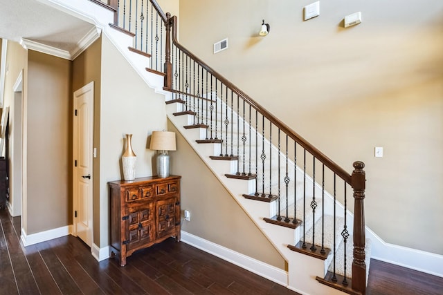 stairs featuring visible vents, baseboards, wood finished floors, and crown molding