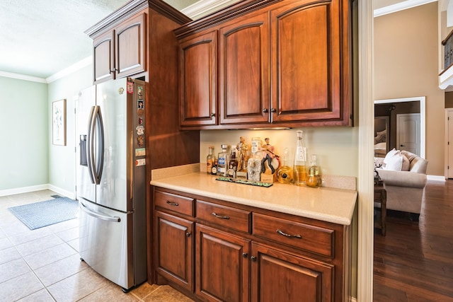 kitchen with crown molding, light countertops, stainless steel fridge, and baseboards