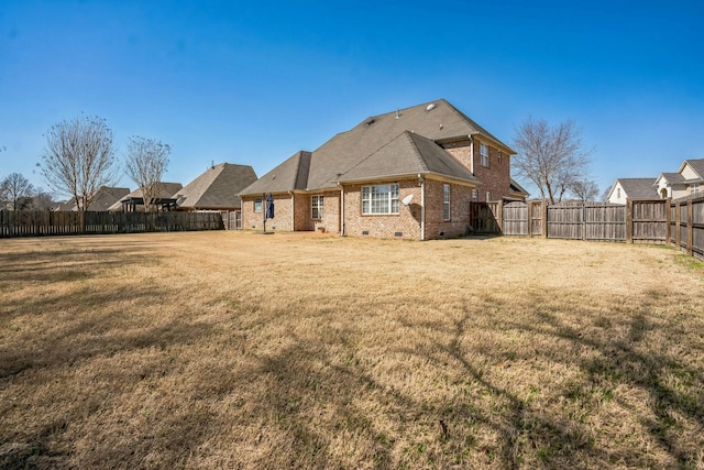 rear view of house with crawl space, brick siding, a fenced backyard, and a lawn