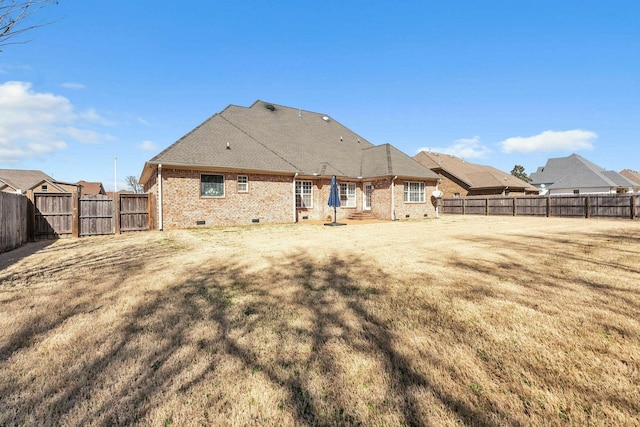 back of property with a lawn, a gate, a fenced backyard, crawl space, and brick siding