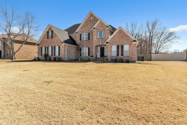 traditional home featuring a gate, brick siding, a front lawn, and fence