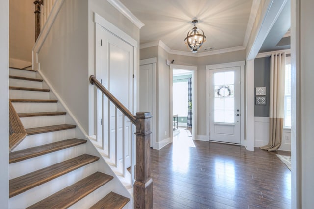 entrance foyer with stairway, wood finished floors, a notable chandelier, and ornamental molding