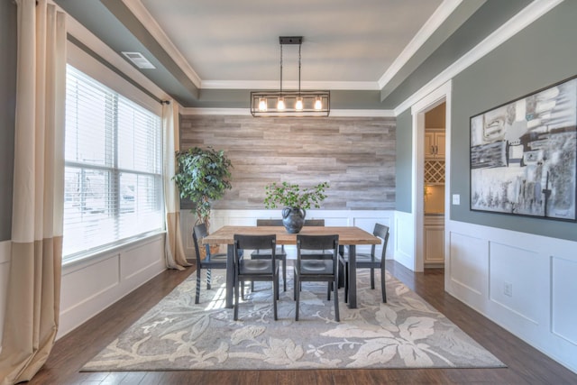 dining area featuring visible vents, dark wood-type flooring, wainscoting, crown molding, and a decorative wall