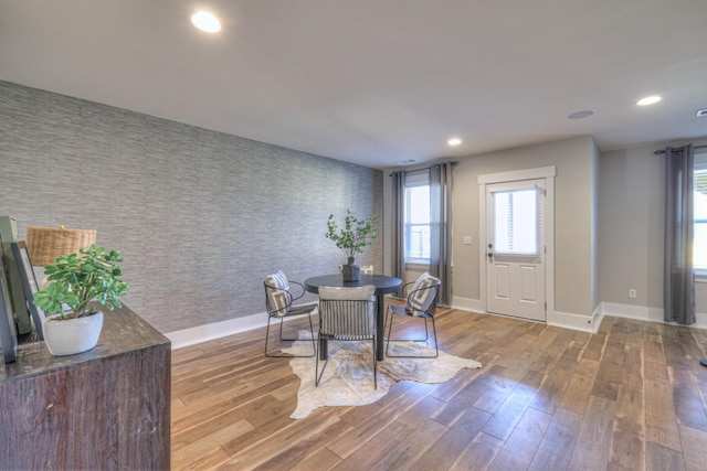 dining room with recessed lighting, wood finished floors, an accent wall, and wallpapered walls