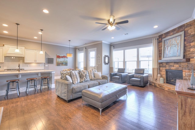 living room featuring dark wood-style floors, baseboards, a fireplace, recessed lighting, and crown molding