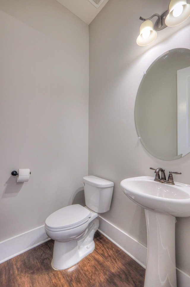 bathroom featuring a sink, toilet, baseboards, and wood finished floors