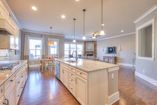 kitchen with a sink, appliances with stainless steel finishes, ornamental molding, and a healthy amount of sunlight