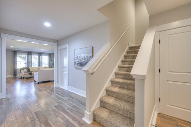 staircase with recessed lighting, baseboards, and wood finished floors