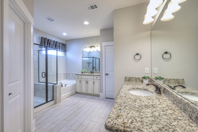 bathroom with a garden tub, visible vents, and a sink