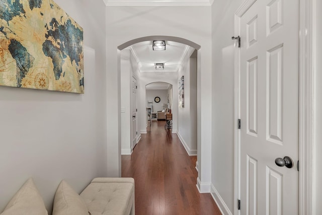 corridor featuring arched walkways, dark wood finished floors, baseboards, and ornamental molding