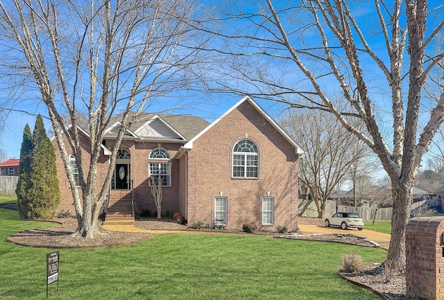 view of front of property featuring brick siding, a front lawn, and fence