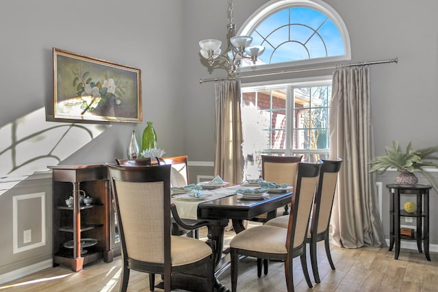 dining space with light wood-style flooring, a notable chandelier, and a high ceiling