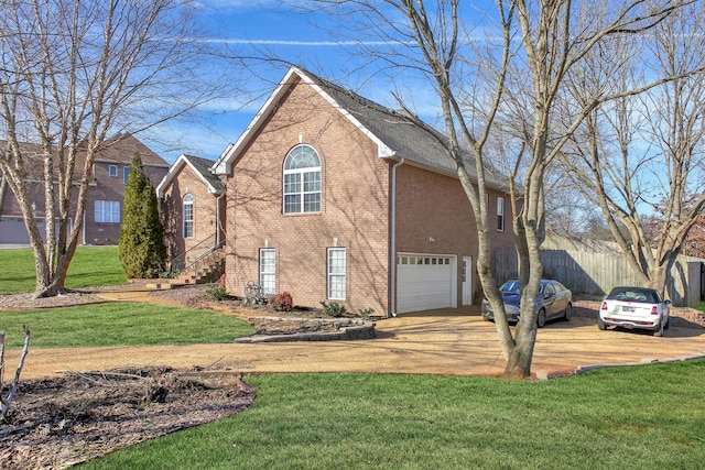 view of front of home featuring brick siding, fence, a front yard, driveway, and an attached garage