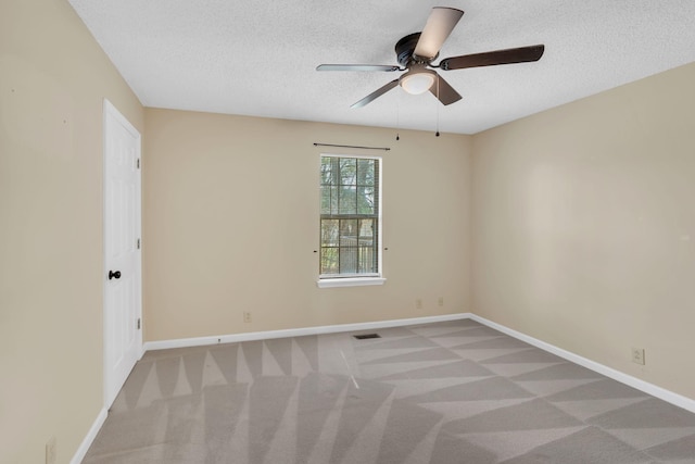 spare room featuring carpet, baseboards, and a textured ceiling