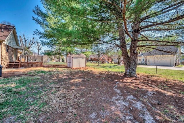 view of yard featuring fence, a storage shed, a deck, a garage, and an outdoor structure