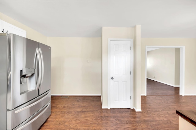 kitchen featuring baseboards, stainless steel fridge, dark wood finished floors, and white cabinetry