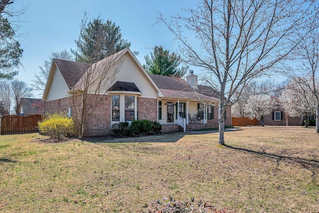 ranch-style house featuring brick siding, a chimney, a front yard, and fence