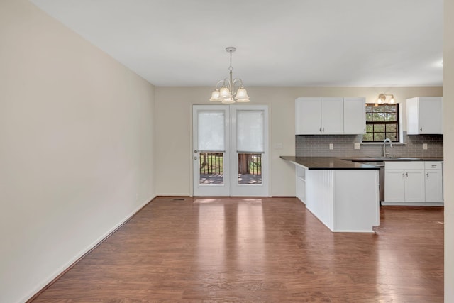 kitchen with a sink, a notable chandelier, dark countertops, and decorative backsplash