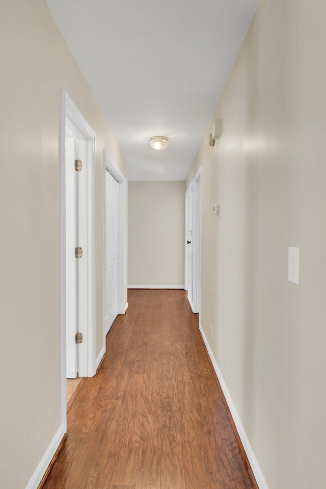 corridor with baseboards and wood finished floors