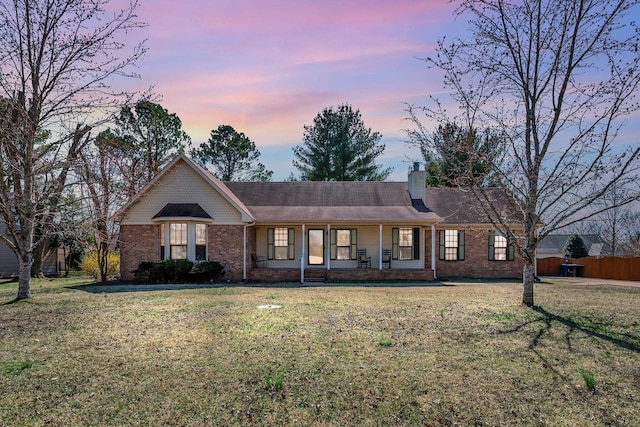 single story home featuring a front lawn, a porch, brick siding, and a chimney