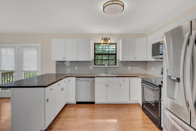 kitchen with light wood-type flooring, a sink, white cabinetry, appliances with stainless steel finishes, and a peninsula