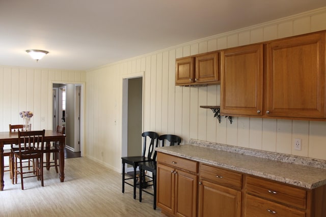 kitchen with brown cabinetry, baseboards, light countertops, and light wood-style floors