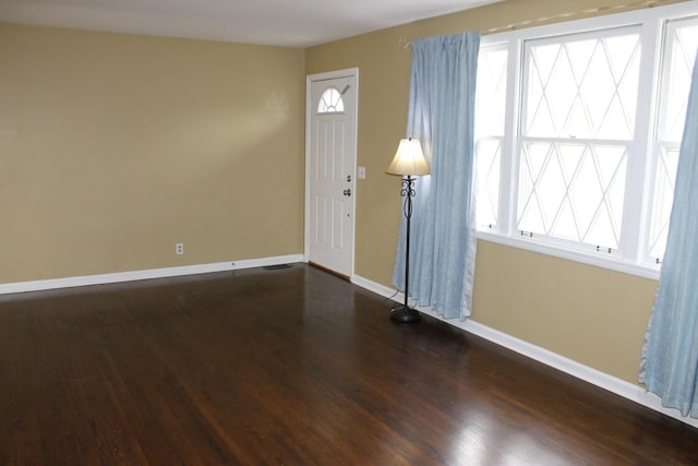 interior space featuring visible vents, baseboards, and dark wood finished floors