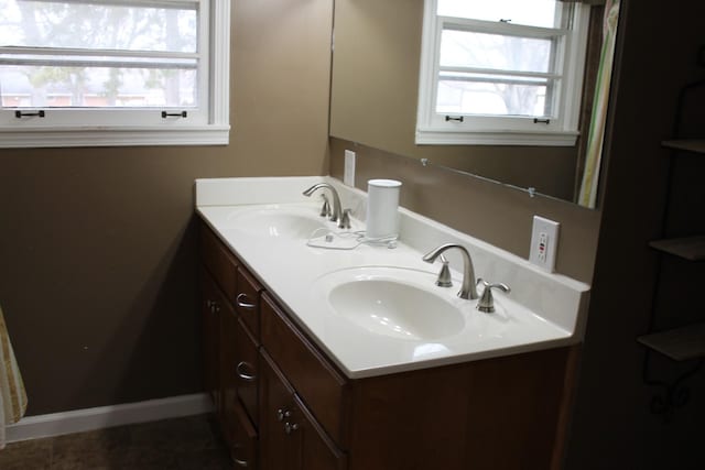 bathroom featuring double vanity, baseboards, and a sink