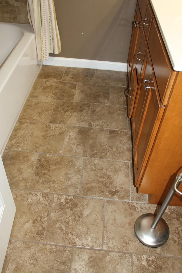 details with baseboards, a shower with shower curtain, and a tub to relax in