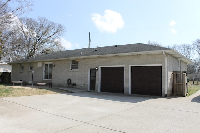 view of front of home with concrete driveway, an attached garage, brick siding, and roof with shingles