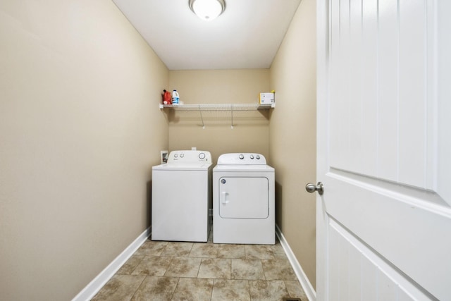 clothes washing area with laundry area, washer and dryer, and baseboards