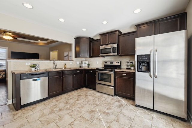 kitchen with a sink, tasteful backsplash, stainless steel appliances, dark brown cabinetry, and light stone countertops