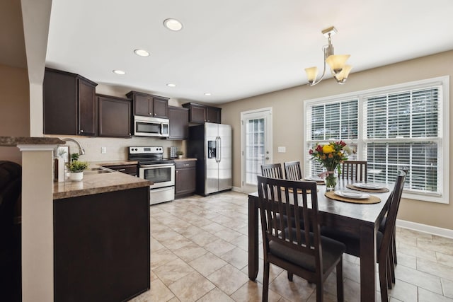 kitchen with baseboards, a sink, decorative backsplash, dark brown cabinets, and appliances with stainless steel finishes