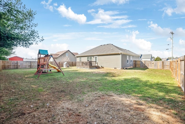 view of yard featuring a deck, a playground, and a fenced backyard