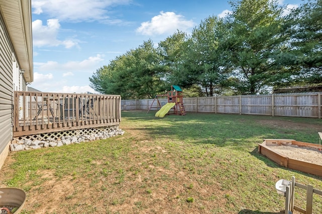 view of yard with a deck, a fenced backyard, and a playground